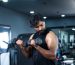 Young man exercising with dumbbells for biceps at gym - concept of bodybuilding, fitness training center, healthy lifestyle, weight lifting and recreational activity