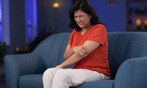 woman-elbow-pain-sitting-on-sofa
